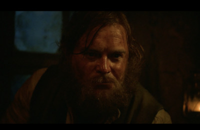 a man with long hair and a beard in a dark room