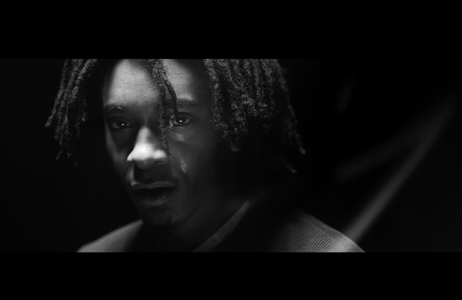 a black and white photo of a man with dreadlocks