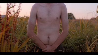 a naked man standing in a field of tall grass