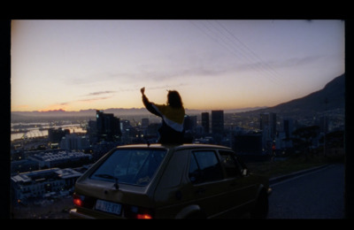 a woman standing on top of a car in front of a city