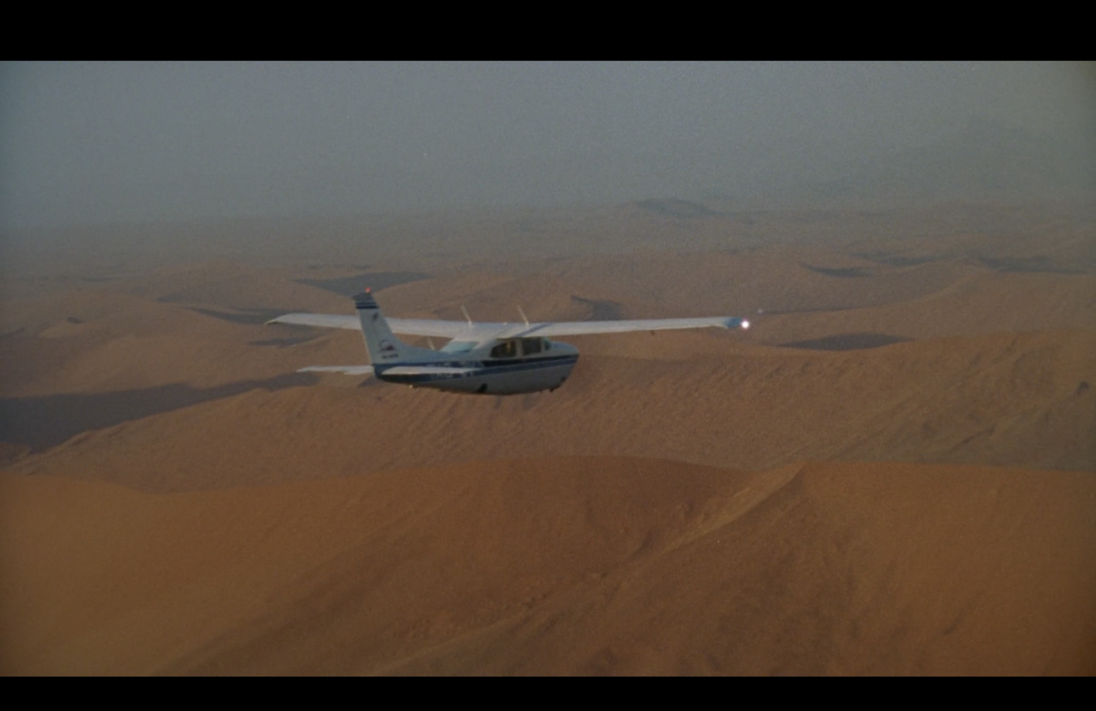 a small airplane flying over a desert landscape