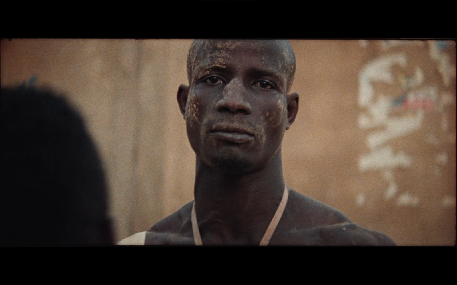 a man with mud on his face standing in front of a wall