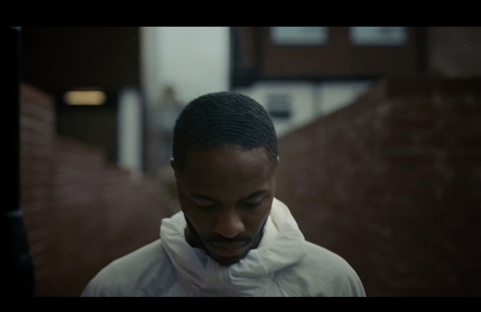 a man in a white jacket looking down at his cell phone