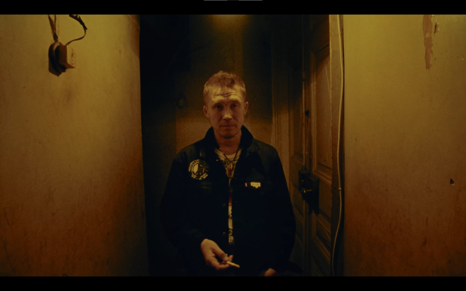 a man standing in a hallway with a cigarette in his hand