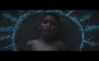 a young boy laying on the ground in the dark