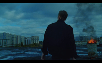 a man standing in front of a fire with a city in the background