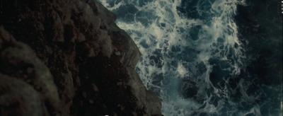 a man standing on top of a cliff next to the ocean