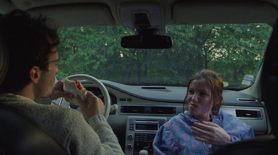 a man and a woman sitting in a car eating food