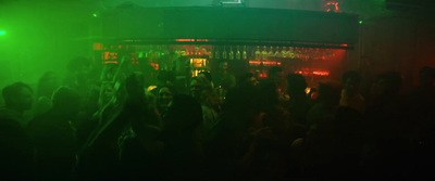 a crowd of people standing around a bar at night