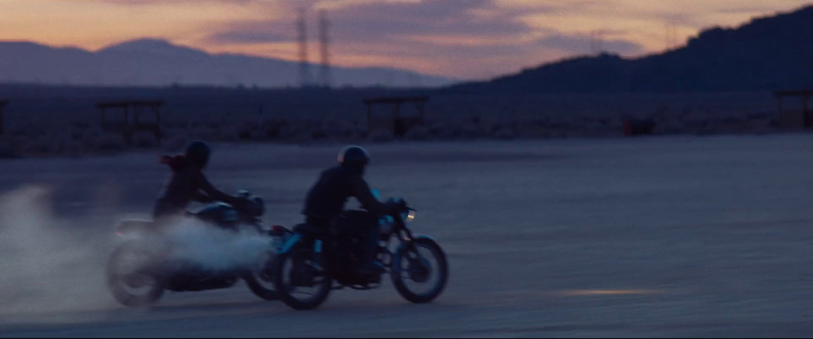 two people riding motorcycles on a dirt road