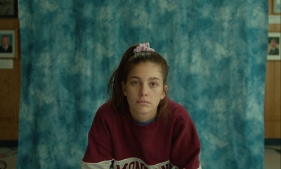 a woman sitting in front of a blue curtain