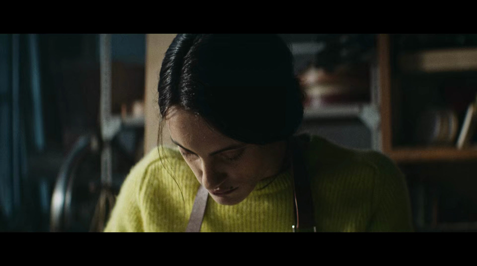 a woman in a yellow sweater is looking down