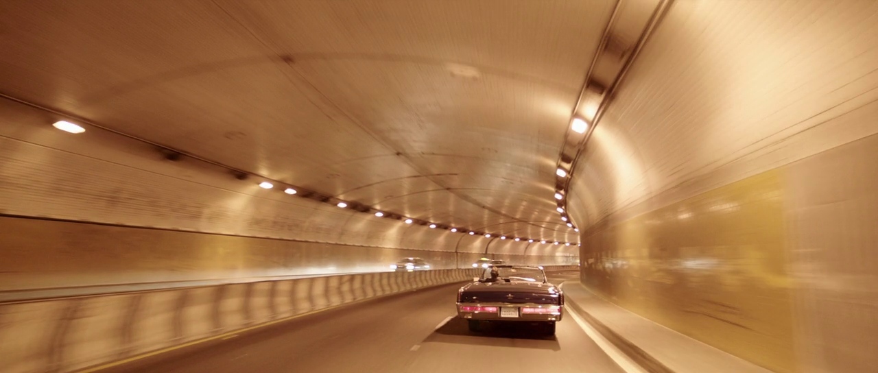 a car driving through a tunnel with lights on