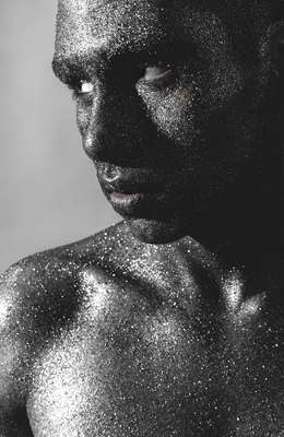 a man is covered in silver glitter with his eyes closed