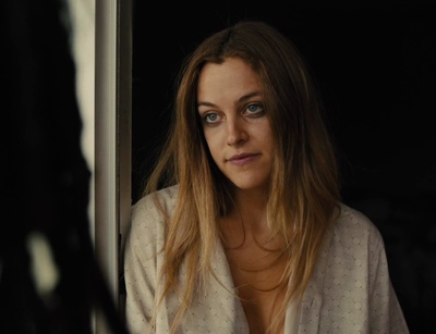 a woman with blue eyes looking out a window