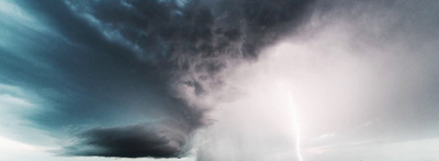 a large cloud is in the sky over a field