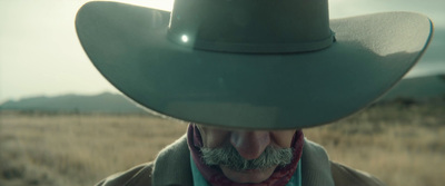 a man wearing a cowboy hat in a field