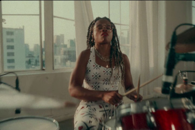 a woman with dreadlocks playing drums in a room