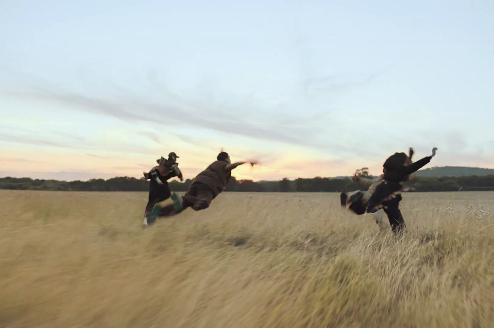 three people jumping in the air in a field