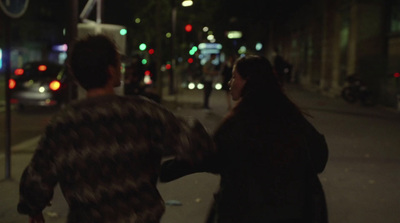 a man and a woman walking down a street at night