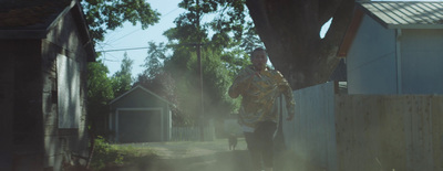 a man walking down a dirt road next to a tree