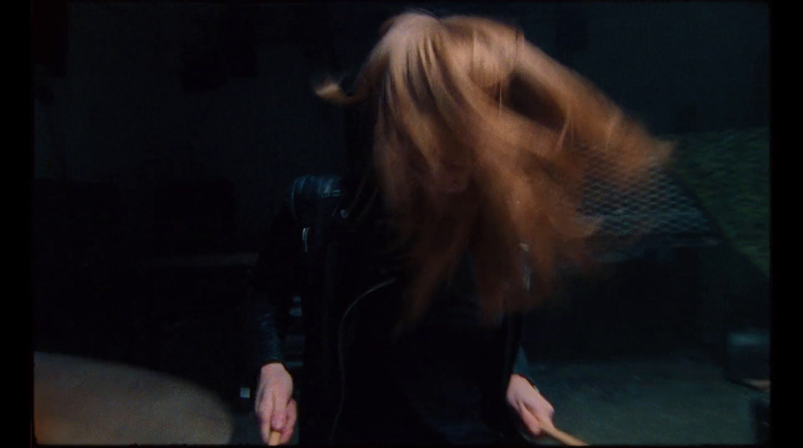 a woman with long red hair standing in a dark room