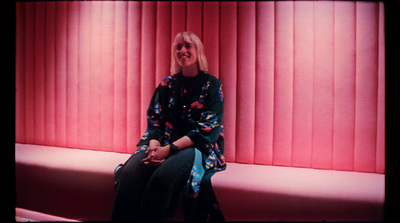 a woman sitting on a bench in front of a red wall