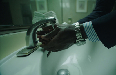 a man in a suit is washing his hands in a sink