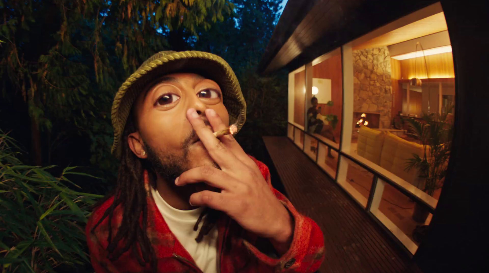 a man smoking a cigarette in front of a house