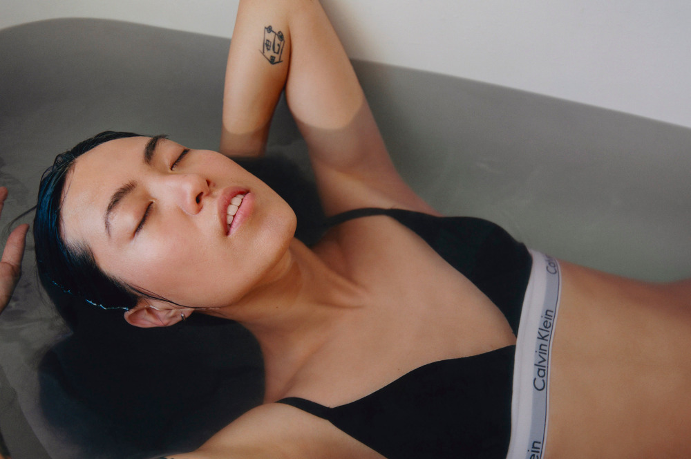 a woman laying in a bathtub with her eyes closed