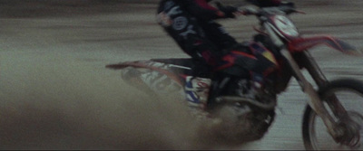 a man riding a dirt bike on top of a sandy beach