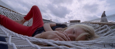 a woman laying in a hammock on a cloudy day