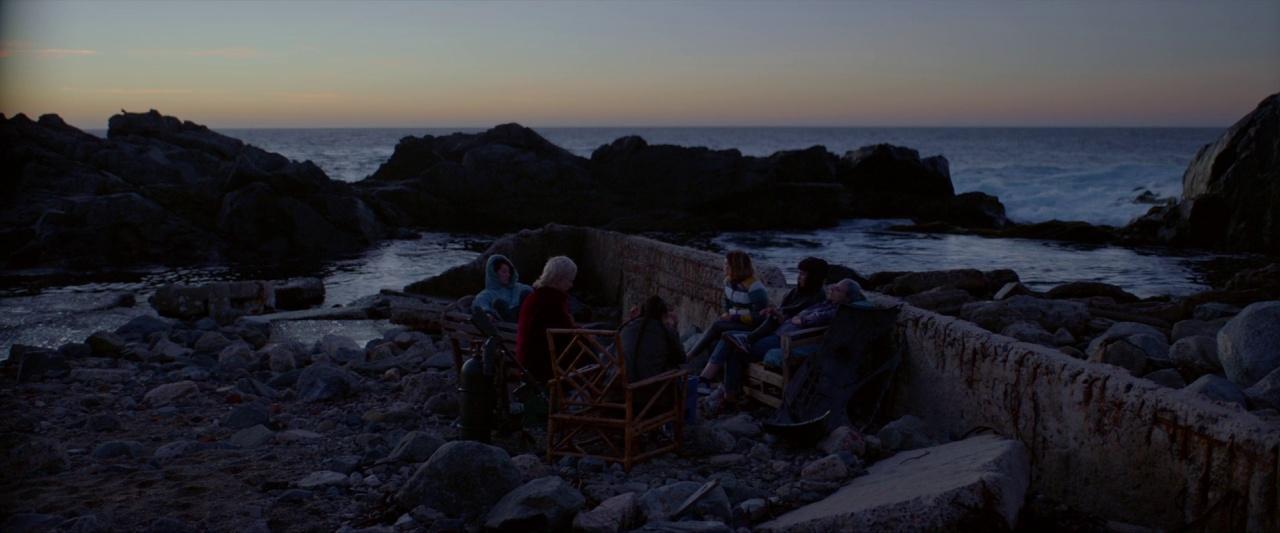 a group of people sitting at a table near the ocean