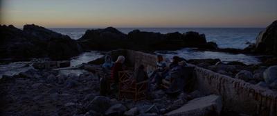 a group of people sitting at a table near the ocean