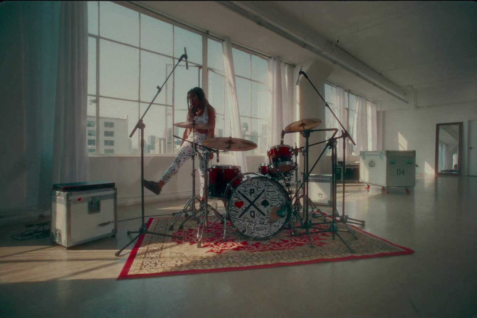 a woman playing drums in front of a window