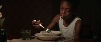 a young boy sitting at a table eating food