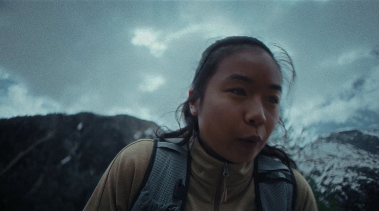 a woman with a backpack standing in front of a mountain