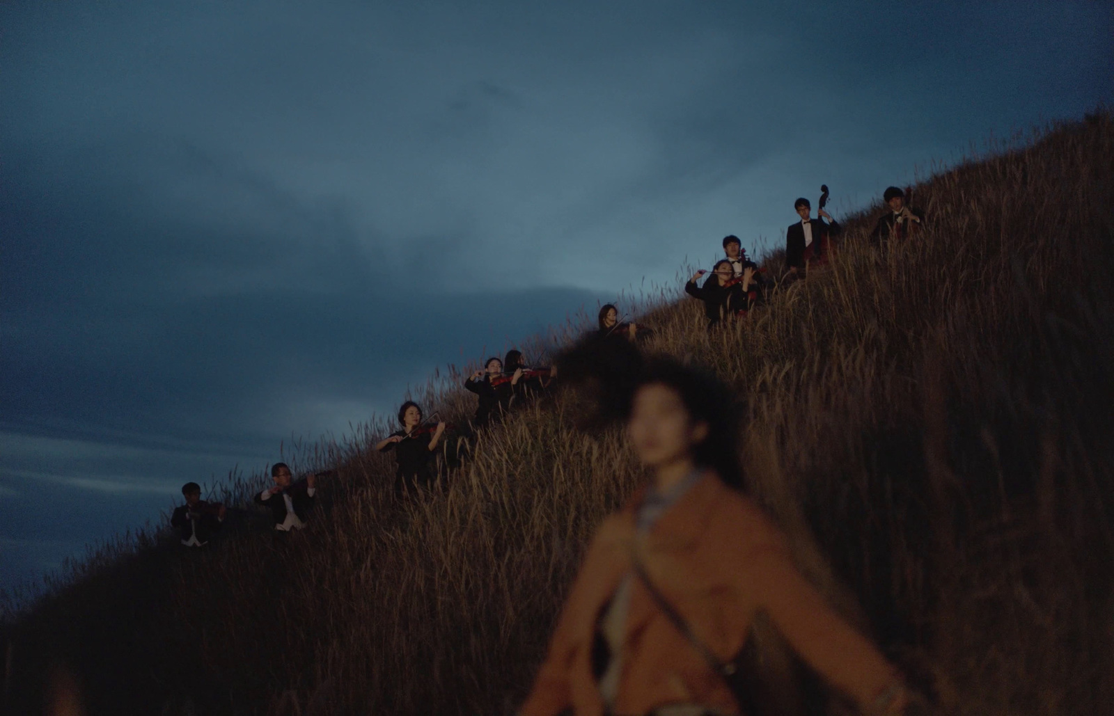 a group of people standing on top of a grass covered hill