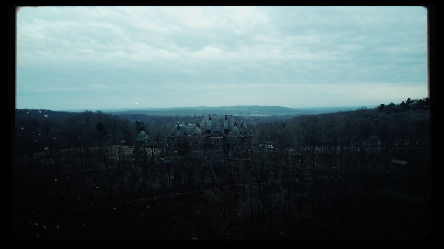 a house in the middle of a forest with mountains in the background