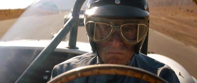 a man wearing goggles and a helmet driving a car