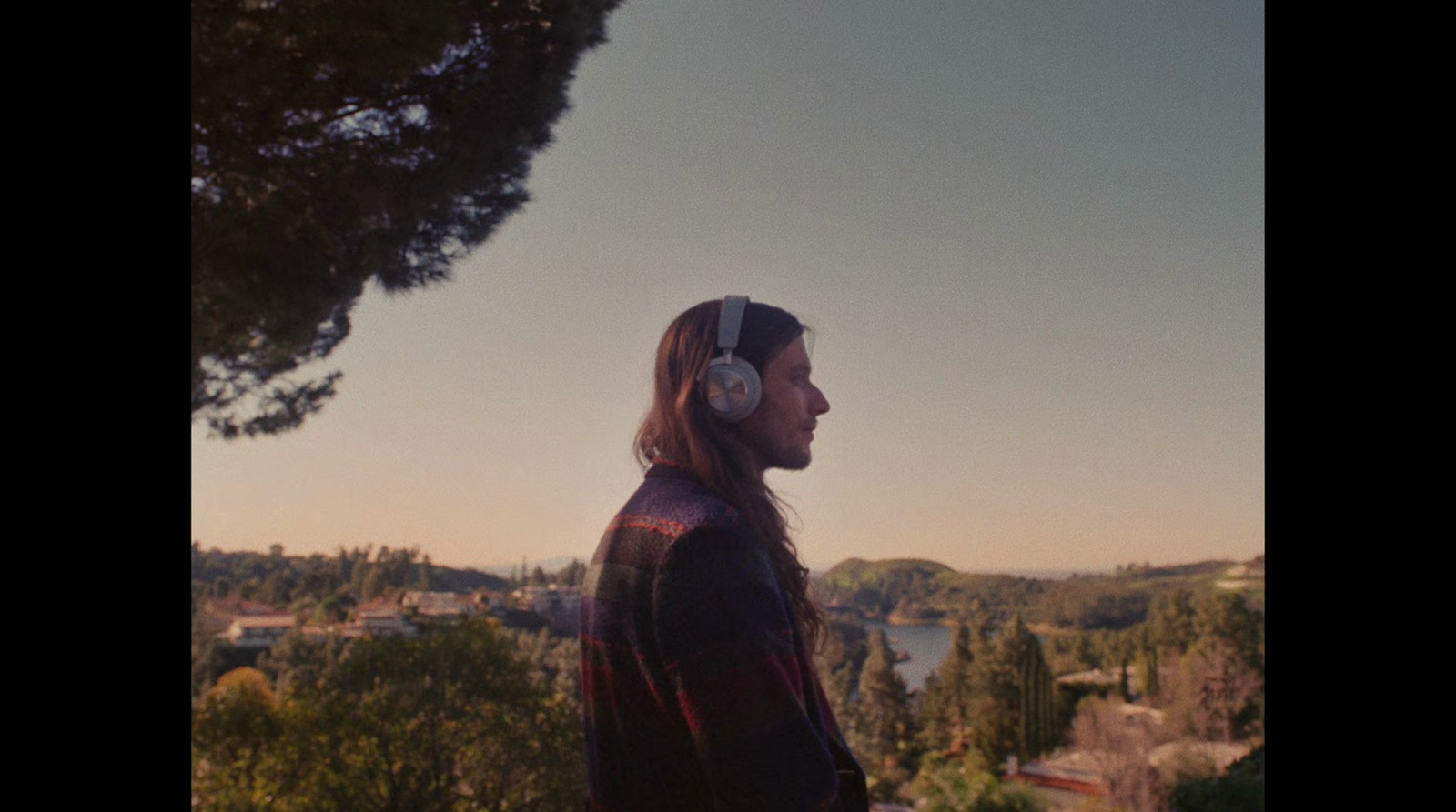 a man with headphones standing in front of a tree