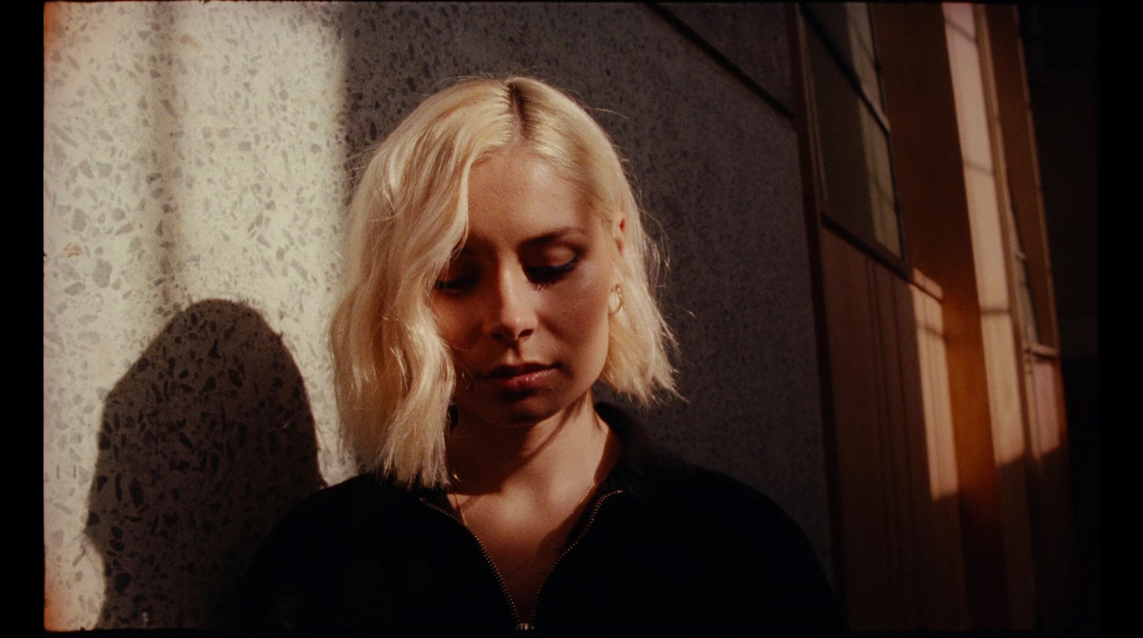 a woman with blonde hair standing in front of a wall