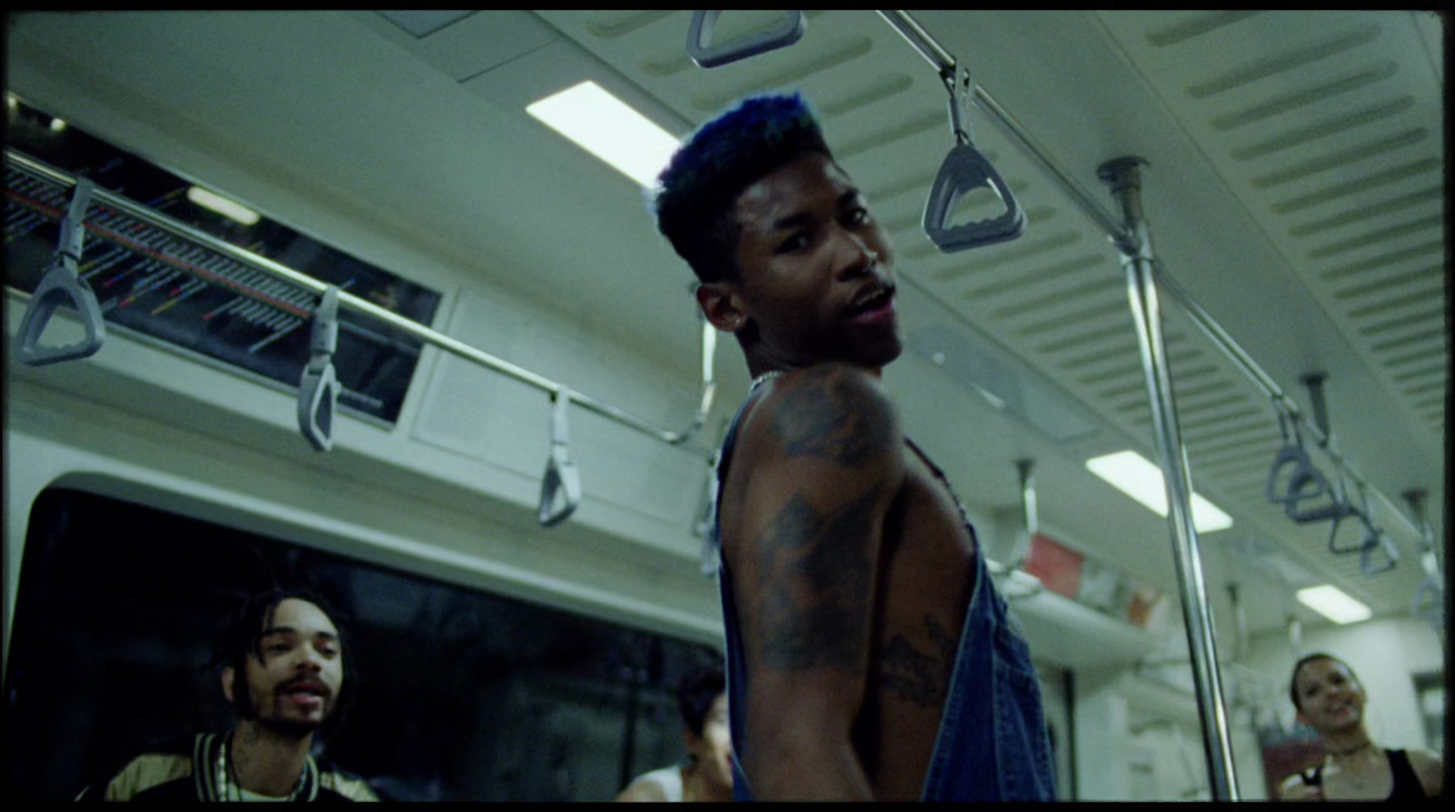 a man with tattoos standing in a subway car