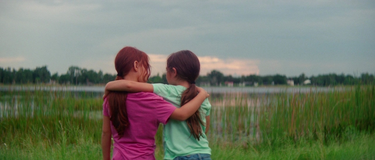 two young girls standing next to each other in a field