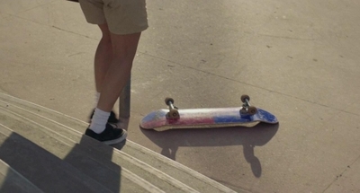 a person standing next to a skateboard on a street