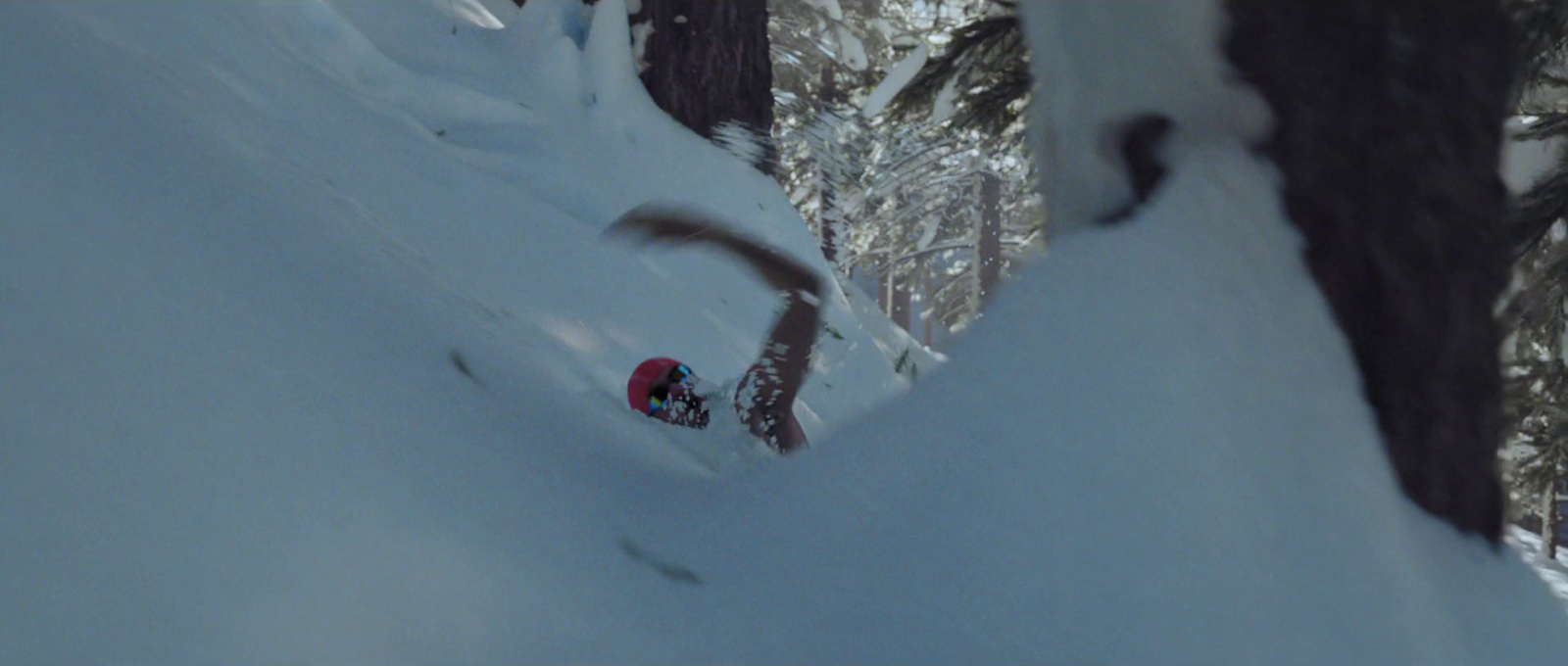 a man riding a snowboard down a snow covered slope