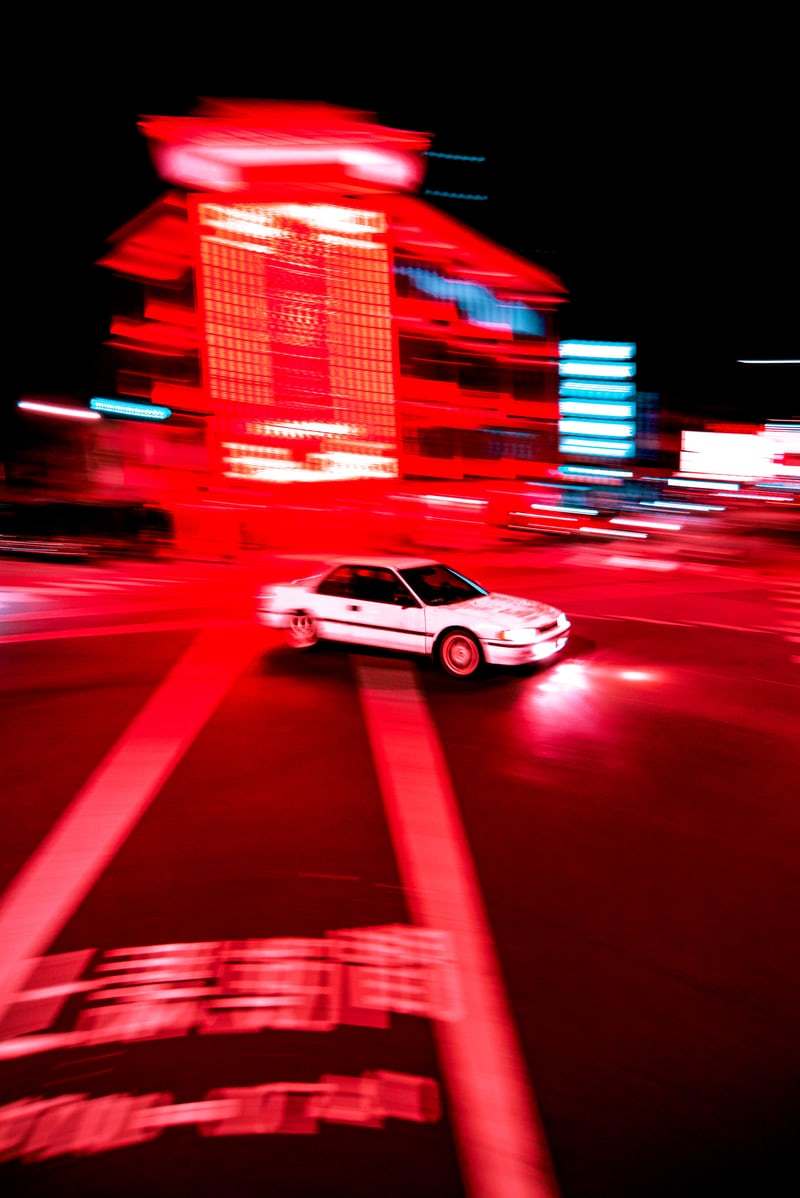 a white car driving down a street at night