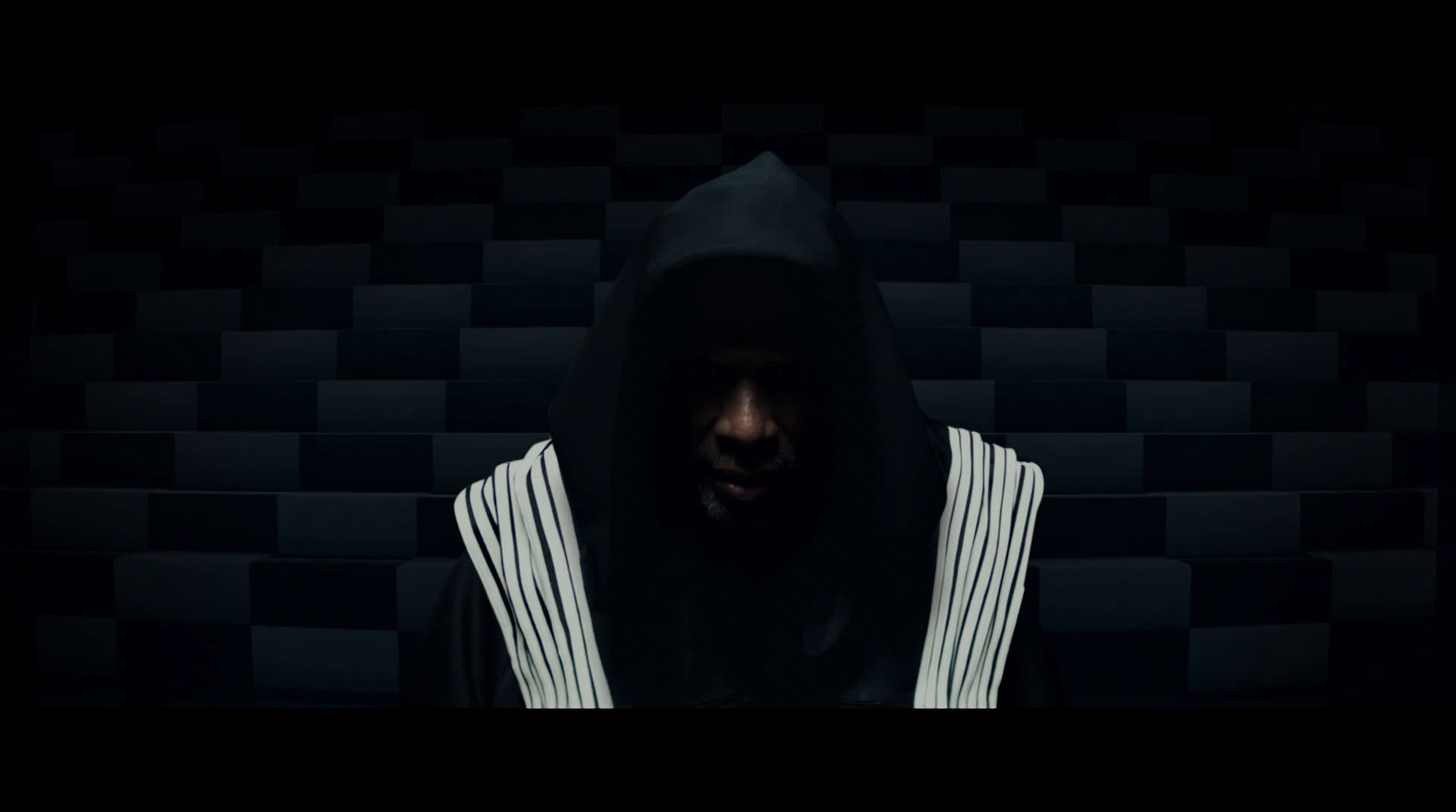 a man with a hoodie on in a dark room