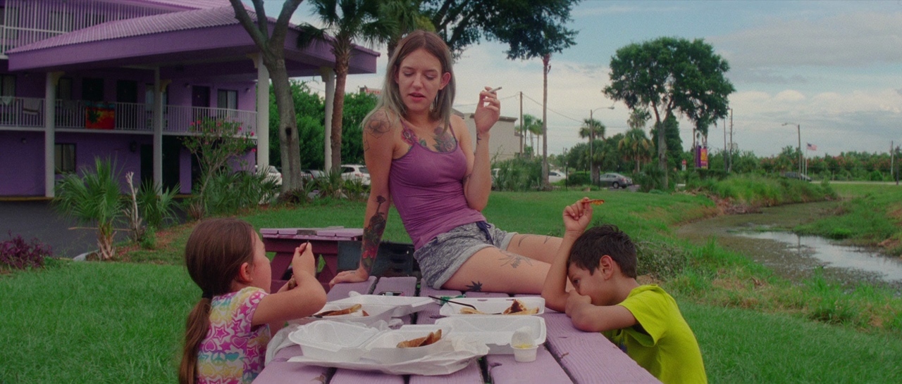 a woman sitting at a picnic table with two children