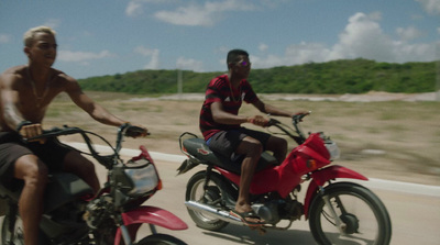 a couple of men riding motorcycles down a road